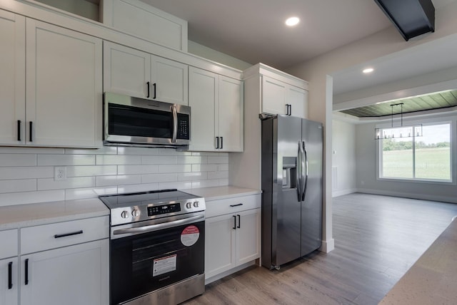 kitchen with tasteful backsplash, white cabinets, stainless steel appliances, and light hardwood / wood-style floors