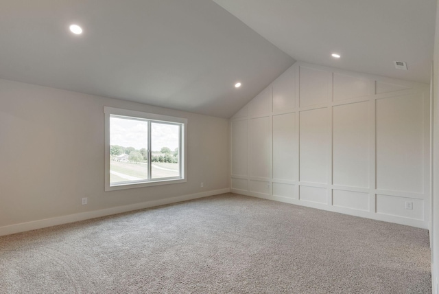 carpeted spare room with lofted ceiling