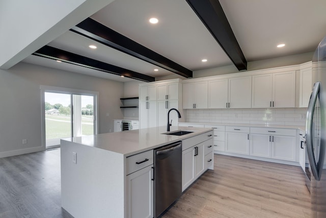 kitchen featuring sink, beamed ceiling, a center island with sink, white cabinets, and appliances with stainless steel finishes