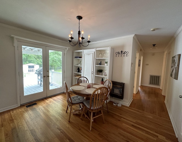 dining area with french doors, heating unit, hardwood / wood-style floors, a chandelier, and ornamental molding