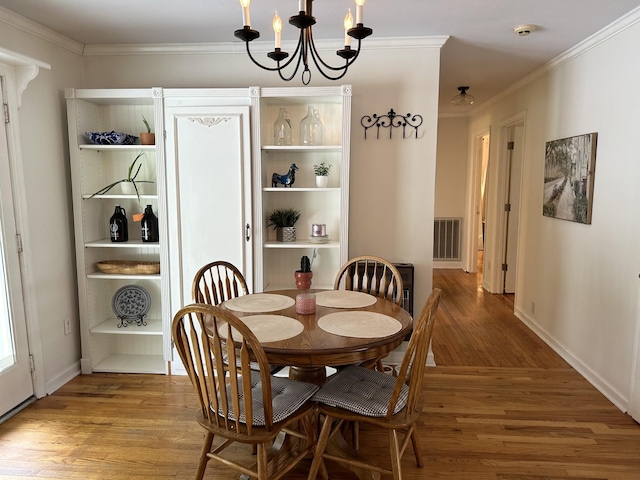 dining space featuring hardwood / wood-style floors, an inviting chandelier, and crown molding