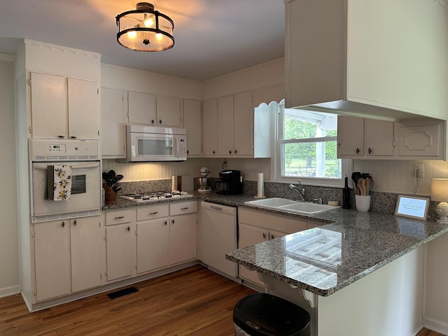 kitchen featuring white appliances, dark wood-type flooring, white cabinets, sink, and dark stone countertops