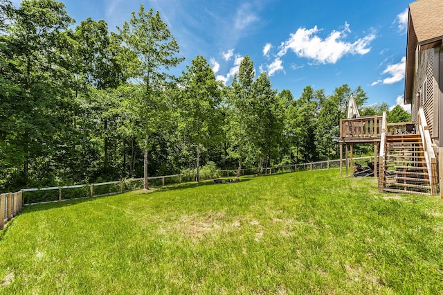 view of yard with a fenced backyard, a wooden deck, and stairs