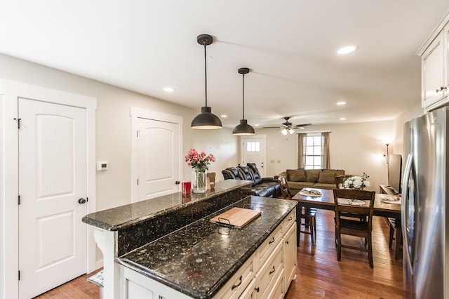 kitchen with white cabinets, a breakfast bar area, freestanding refrigerator, and a center island