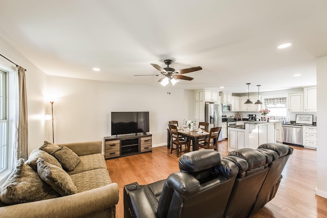 living area featuring light wood-style flooring, baseboards, ceiling fan, and recessed lighting