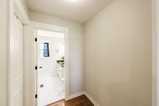 interior space featuring toilet, marble finish floor, baseboards, and vanity