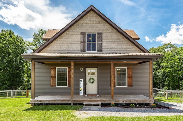 view of front of property with metal roof, fence, a porch, and a front yard