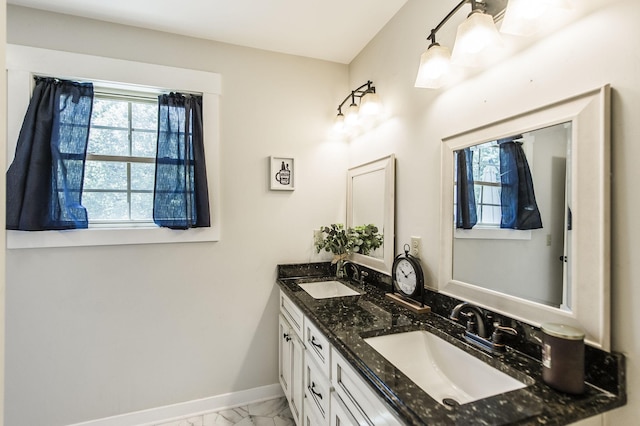 bathroom with marble finish floor, plenty of natural light, and a sink