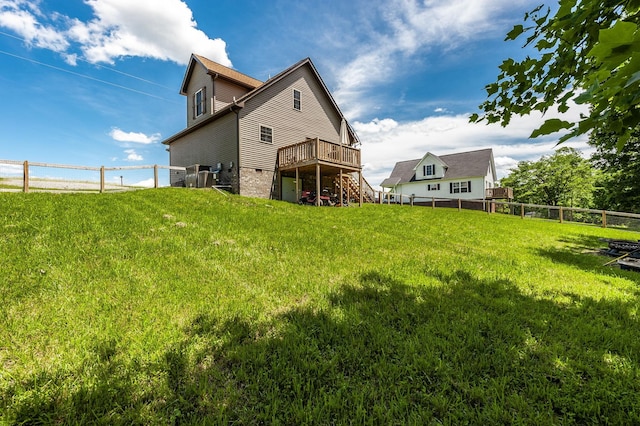 rear view of house featuring a fenced backyard, a lawn, a deck, and stairs