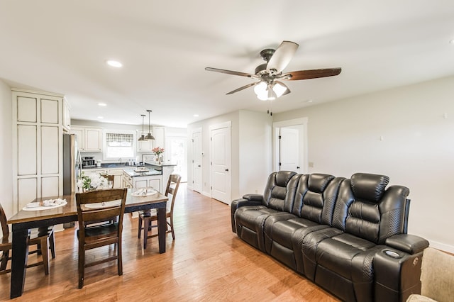 living room featuring light wood-style flooring, baseboards, a ceiling fan, and recessed lighting