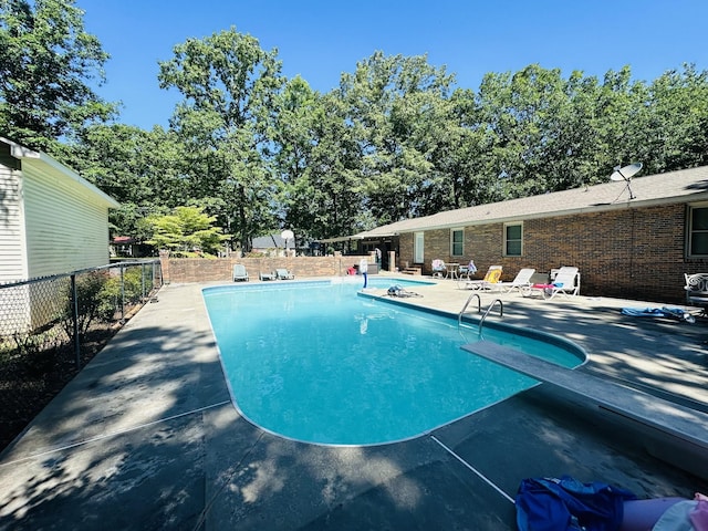 view of swimming pool with a diving board and a patio