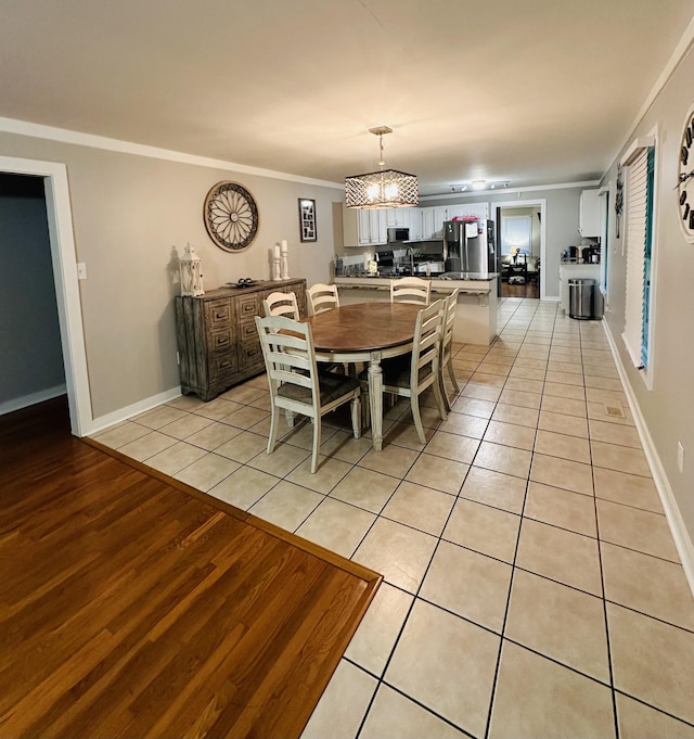 tiled dining area featuring ornamental molding and a chandelier