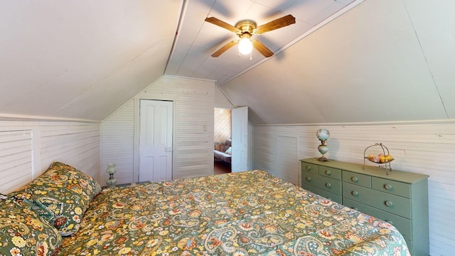 bedroom featuring ceiling fan, wood walls, and vaulted ceiling