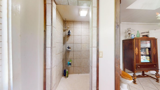 bathroom featuring tile patterned flooring, toilet, and tiled shower