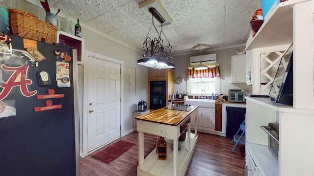 kitchen with pendant lighting, wood counters, a kitchen island, white cabinetry, and a wall unit AC