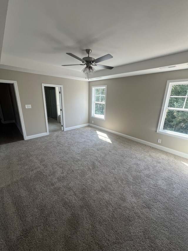 unfurnished bedroom with carpet, a walk in closet, ensuite bathroom, and ceiling fan