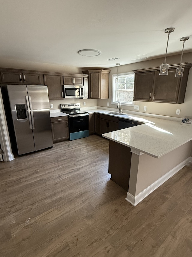 kitchen with kitchen peninsula, appliances with stainless steel finishes, dark brown cabinetry, dark wood-type flooring, and decorative light fixtures