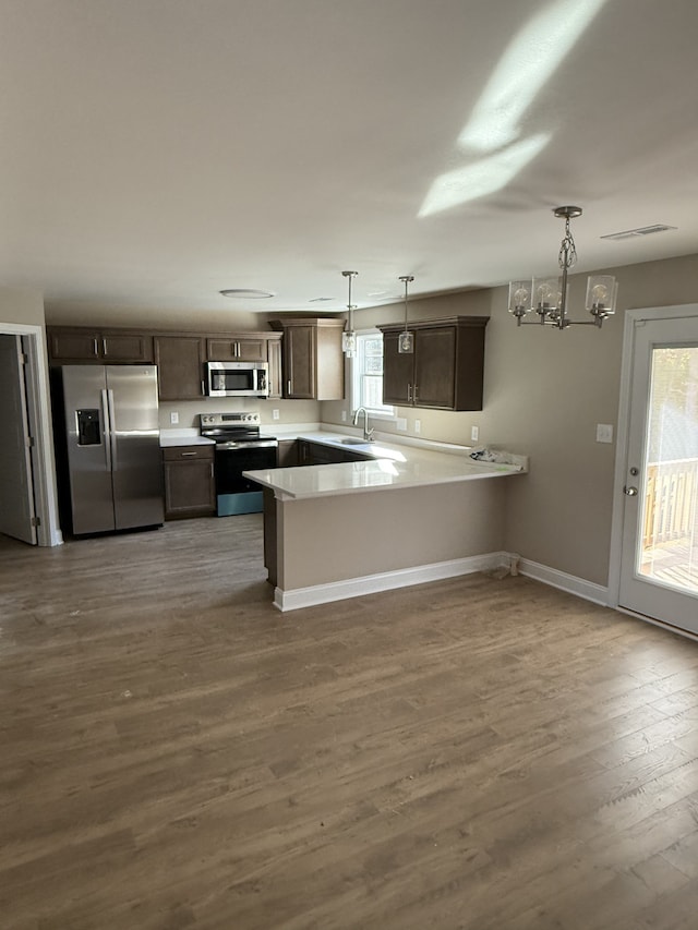 kitchen featuring a wealth of natural light, kitchen peninsula, stainless steel appliances, and hanging light fixtures