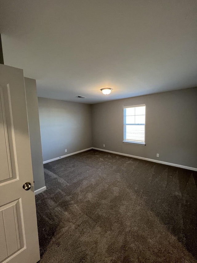 spare room featuring dark carpet