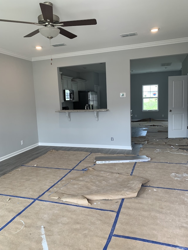 unfurnished living room with ceiling fan and ornamental molding