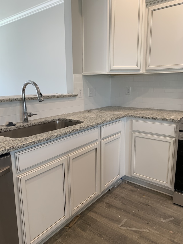 kitchen featuring sink, white cabinets, dark hardwood / wood-style flooring, stainless steel dishwasher, and light stone countertops