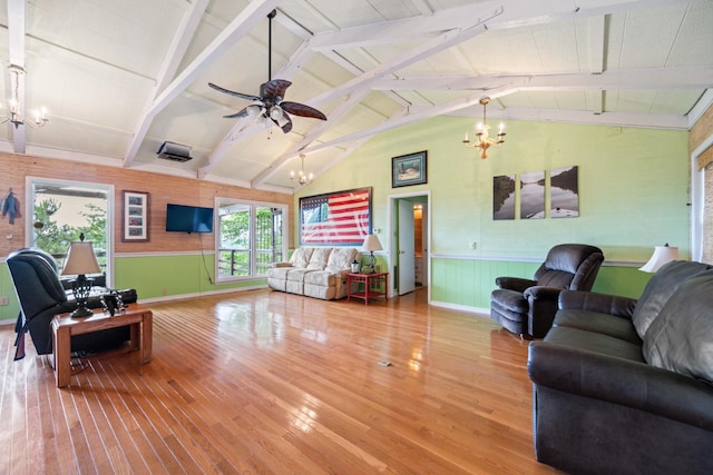 living room with hardwood / wood-style floors, ceiling fan with notable chandelier, and vaulted ceiling with beams