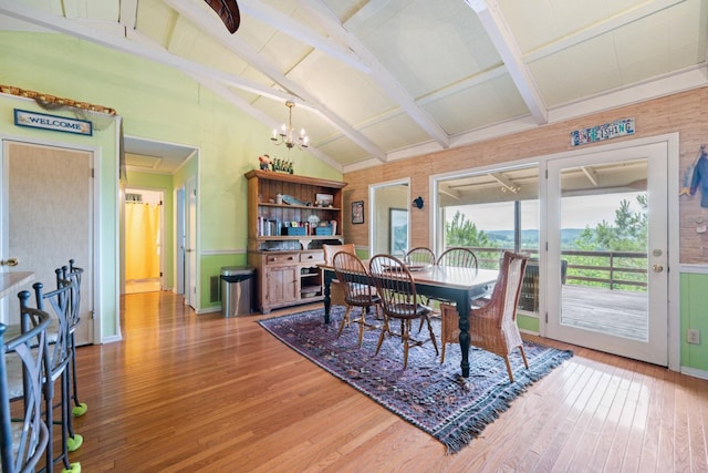 dining area with lofted ceiling with beams, wood-type flooring, and an inviting chandelier