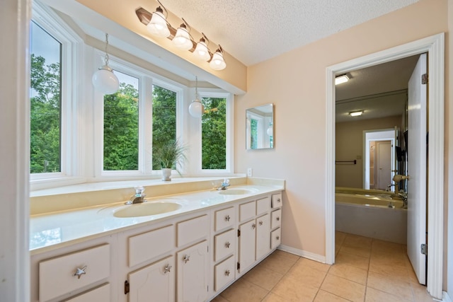 bathroom with vanity, a textured ceiling, tile patterned floors, and a tub