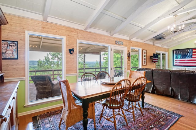 dining room with vaulted ceiling with beams, hardwood / wood-style flooring, wood walls, and an inviting chandelier