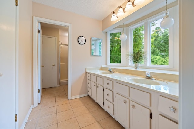 bathroom with tile patterned flooring, vanity, an enclosed shower, and a textured ceiling