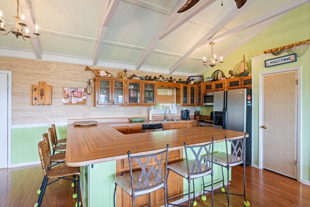 kitchen with an inviting chandelier, dark hardwood / wood-style flooring, lofted ceiling with beams, a breakfast bar, and appliances with stainless steel finishes