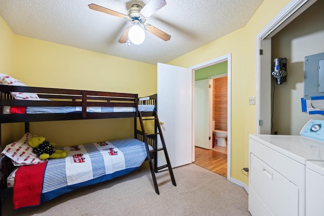 bedroom featuring ensuite bath, light colored carpet, ceiling fan, washing machine and clothes dryer, and electric panel