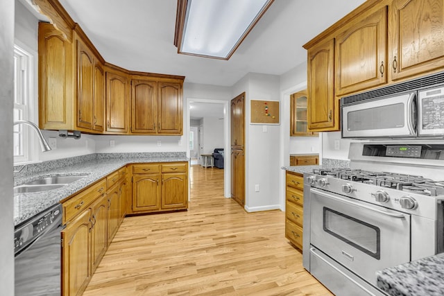 kitchen with light stone counters, sink, light wood-type flooring, and stainless steel appliances