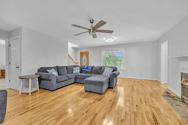 living room featuring ceiling fan, a fireplace, and light hardwood / wood-style floors