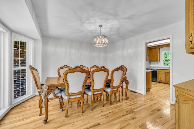 dining area with light wood-type flooring and a notable chandelier