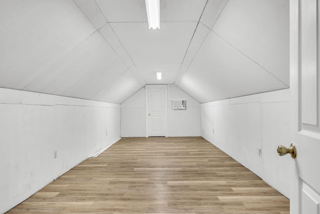 additional living space with light hardwood / wood-style flooring and lofted ceiling