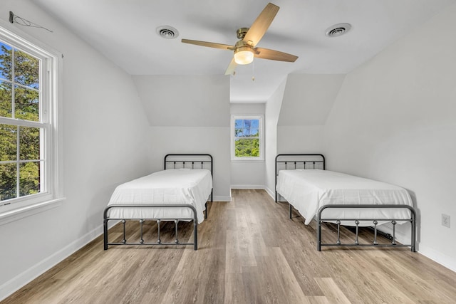 bedroom with ceiling fan, lofted ceiling, and light wood-type flooring