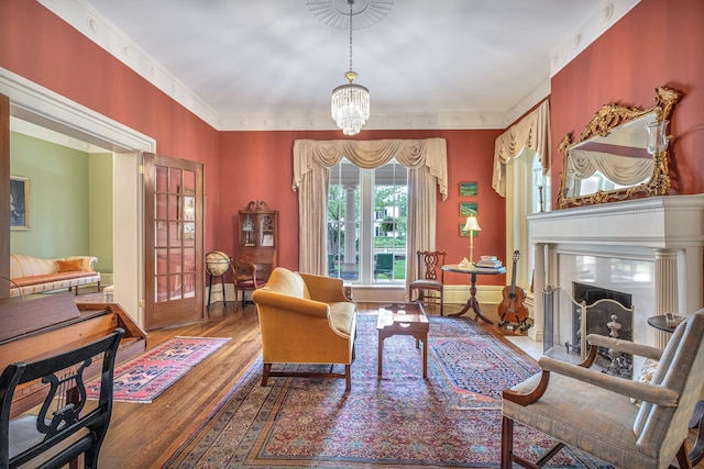 living area featuring hardwood / wood-style flooring, an inviting chandelier, crown molding, and a premium fireplace