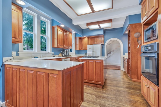 kitchen featuring beamed ceiling, kitchen peninsula, wood-type flooring, white appliances, and a kitchen island