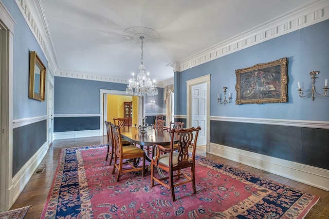 dining space with crown molding, dark wood-type flooring, and an inviting chandelier