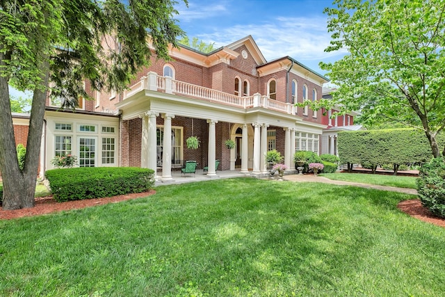 back of property with a lawn and a balcony