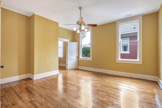 spare room featuring light wood-type flooring, ceiling fan, and ornamental molding