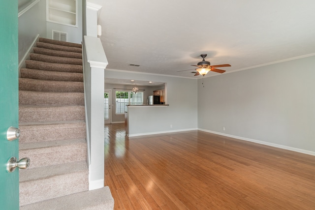 interior space featuring hardwood / wood-style flooring, crown molding, and ceiling fan with notable chandelier