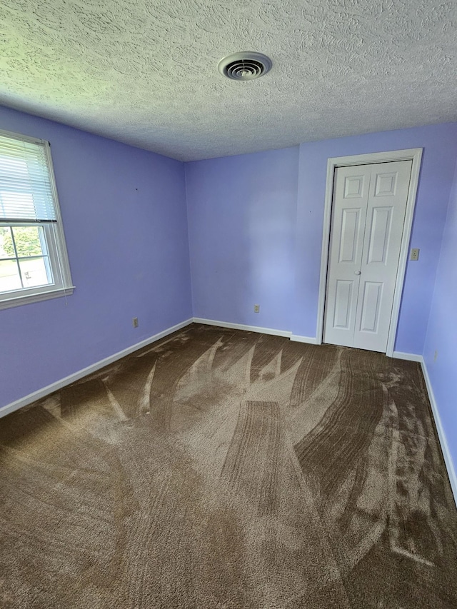 unfurnished room with carpet flooring and a textured ceiling