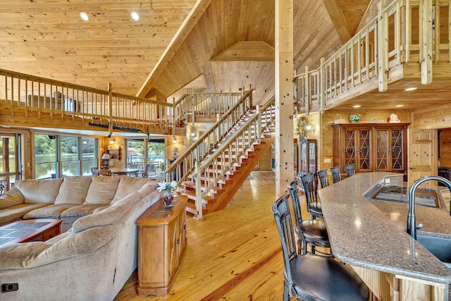 living room with sink, light hardwood / wood-style floors, wood walls, high vaulted ceiling, and wood ceiling