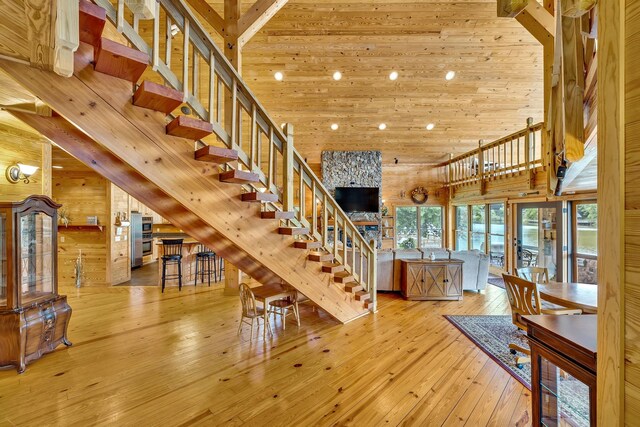 staircase featuring hardwood / wood-style floors, wooden walls, and high vaulted ceiling