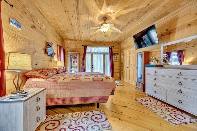 bedroom featuring ceiling fan, light hardwood / wood-style flooring, wooden ceiling, and wooden walls