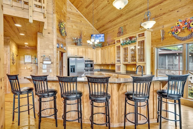 kitchen with wood ceiling, stainless steel appliances, a kitchen bar, and high vaulted ceiling