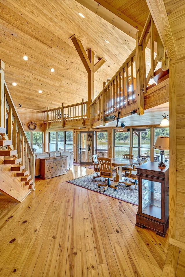 interior space with light hardwood / wood-style floors, wooden walls, wooden ceiling, and high vaulted ceiling