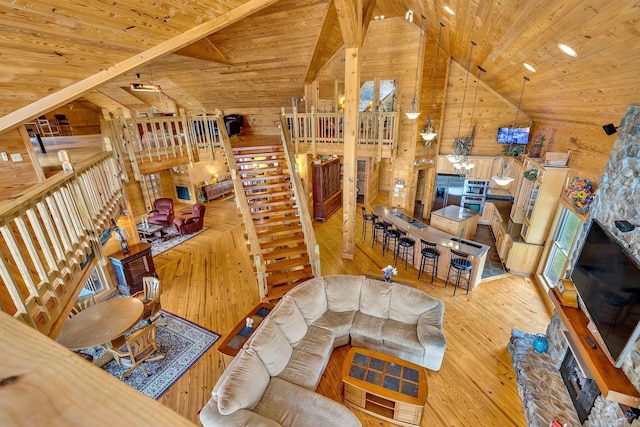 living room featuring light wood-type flooring, wooden walls, lofted ceiling with beams, and wood ceiling